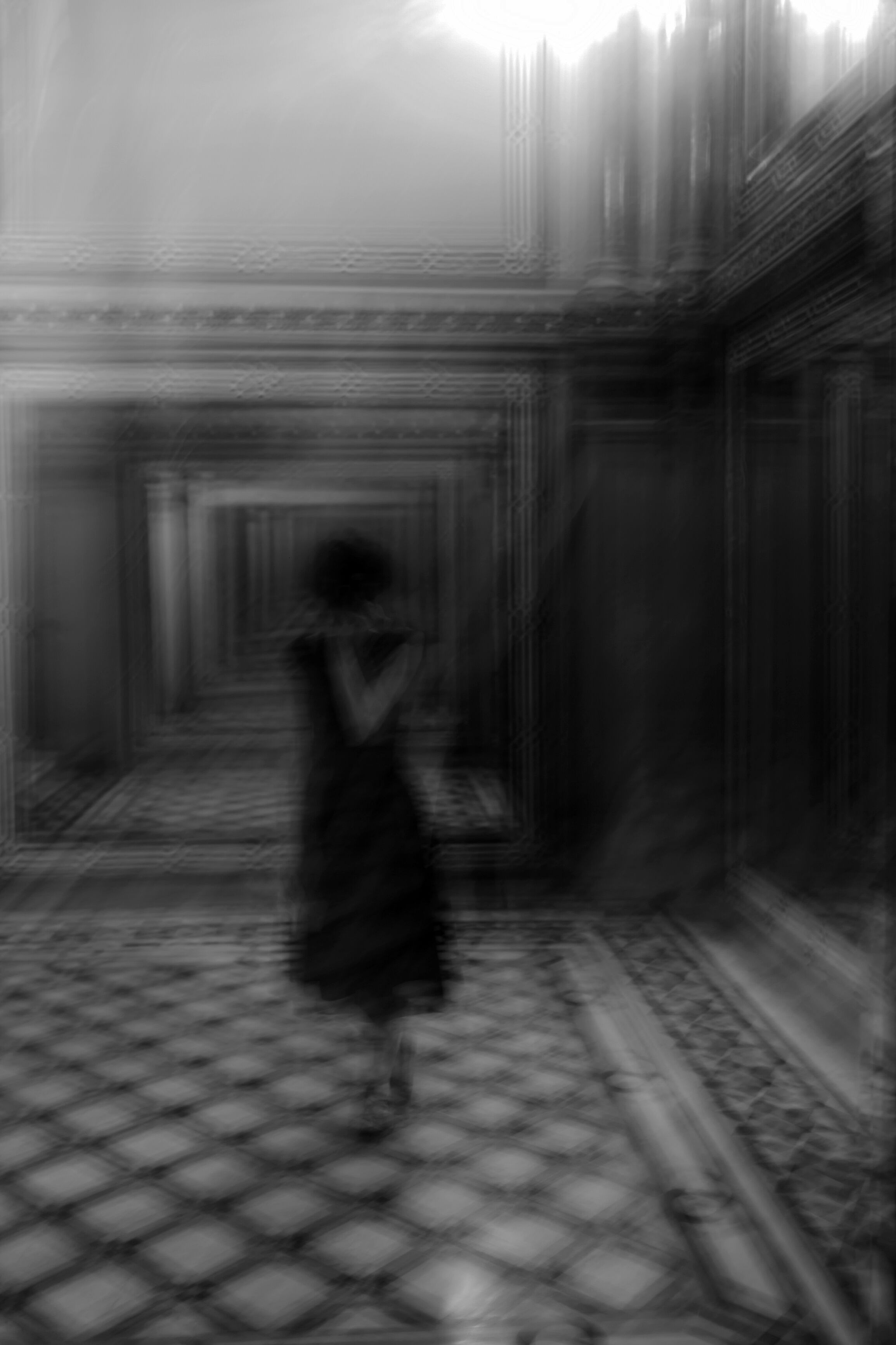 A blurred silhouette of a person walking through a  hallway