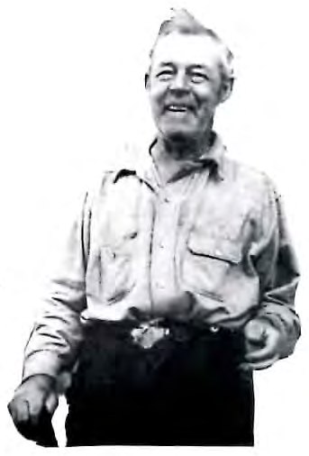 Black-and-white photograph of a smiling older man in a work shirt, standing outdoors.