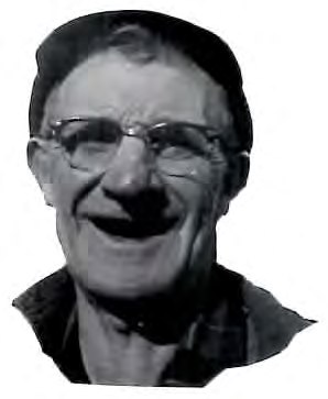 Black-and-white close-up photograph of a smiling man wearing glasses and a cap.