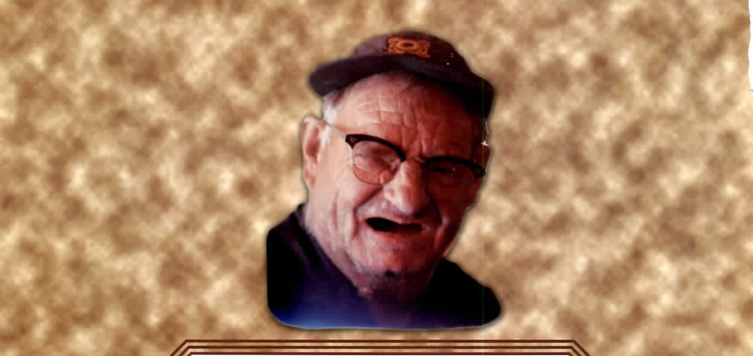 Black and white photograph of an older man wearing glasses and a cap, laughing, head and shoulders only