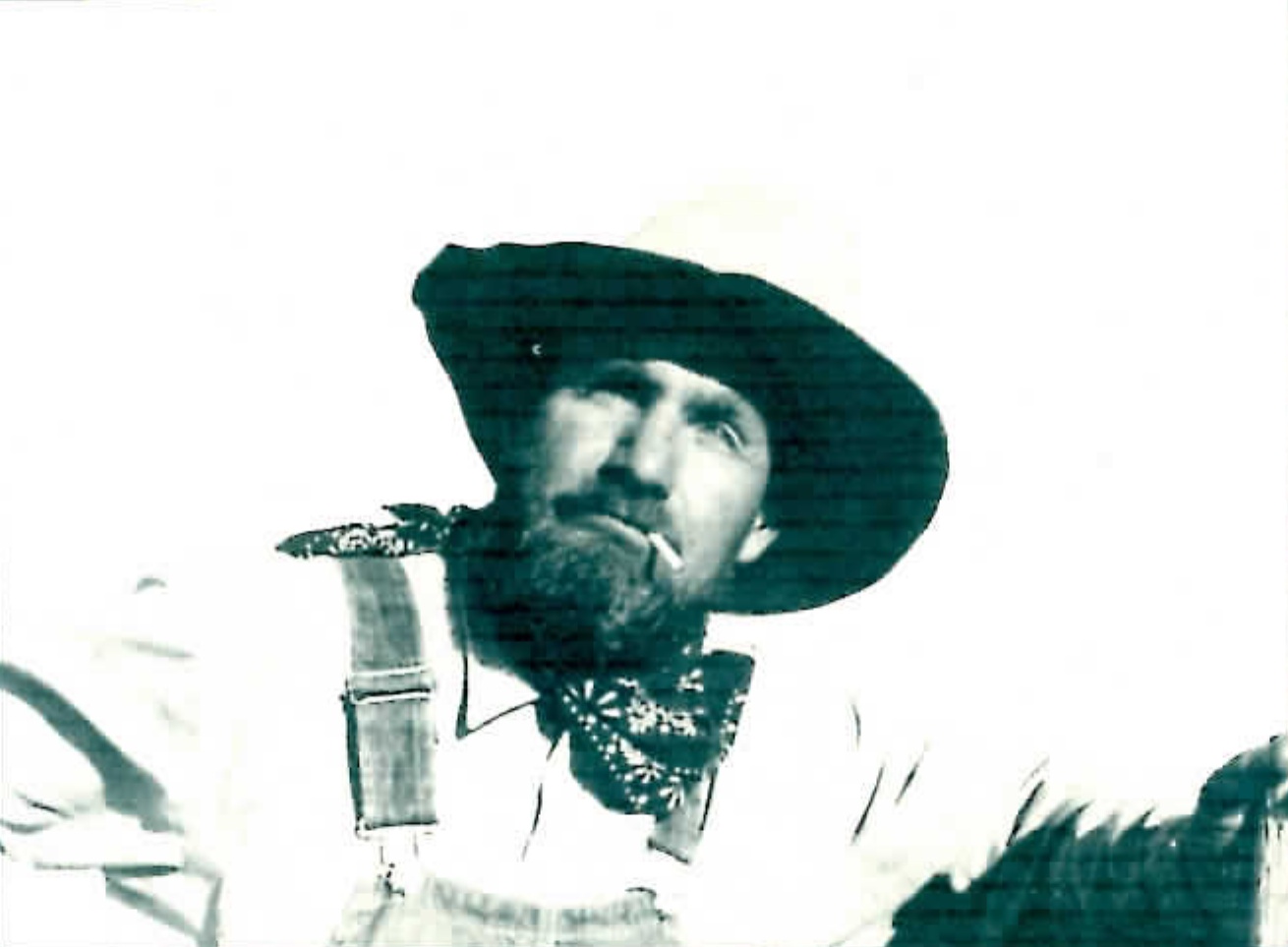 Black-and-white photograph of John Richard Jackson dressed as an old-time miner, wearing a wide-brimmed hat and a bandana and smoking a cigarette, from the back cover of "Once Around the Thunder Mug."